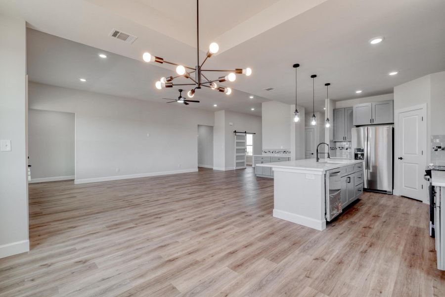 Kitchen with stainless steel appliances, gray cabinetry, a sink, a chandelier, and open floor plan