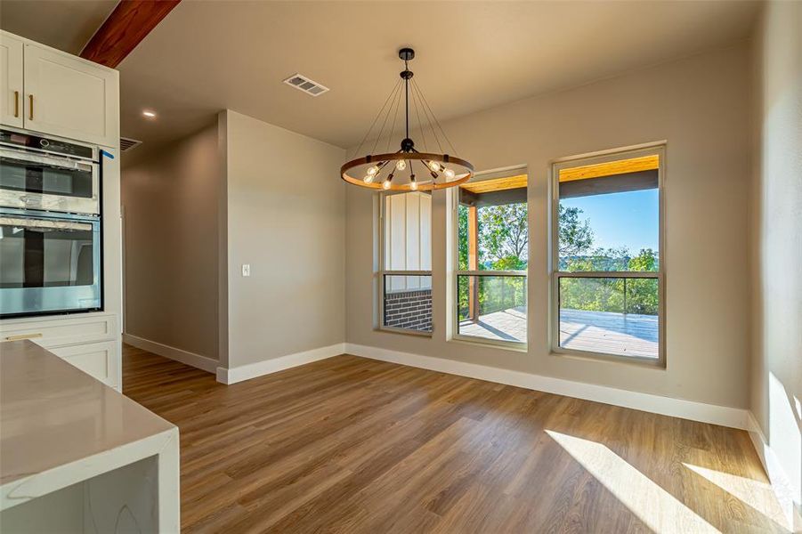 Unfurnished dining area with light wood finished floors, a chandelier, and recessed lighting Unfurnished dining area with light wood finished floors, a chandelier, and recessed lighting