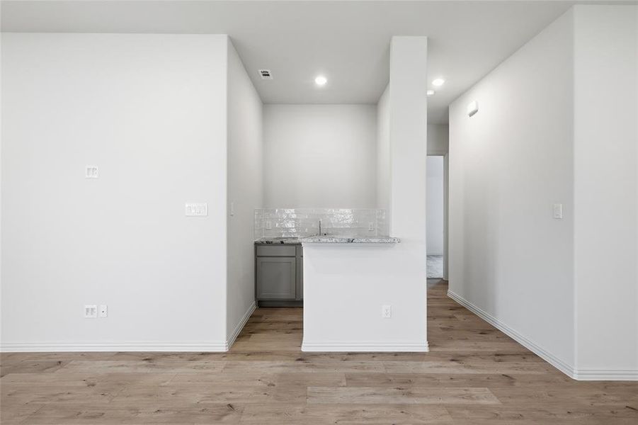 Built-in wet bar featuring a single basin sink, white subway tile backsplash, and light-toned countertop Built-in wet bar featuring a single basin sink, white subway tile backsplash, and light-toned countertop