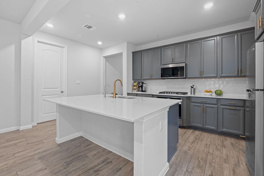 Kitchen featuring decorative backsplash, stainless steel appliances, recessed lighting, light wood-type flooring, and a kitchen island with sink Kitchen featuring decorative backsplash, stainless steel appliances, recessed lighting, light wood-type flooring, and a kitchen island with sink