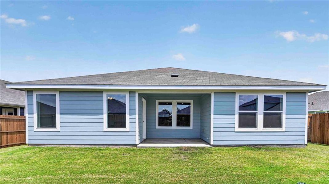 Rear exterior featuring light blue siding, a covered patio with concrete flooring, multiple windows with white trim, and a shingled roof Rear exterior featuring light blue siding, a covered patio with concrete flooring, multiple windows with white trim, and a shingled roof