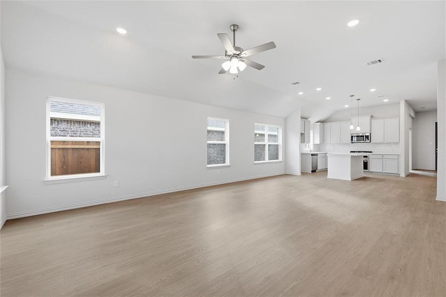 Unfurnished living room with light wood finished floors, recessed lighting, a ceiling fan, and vaulted ceiling
