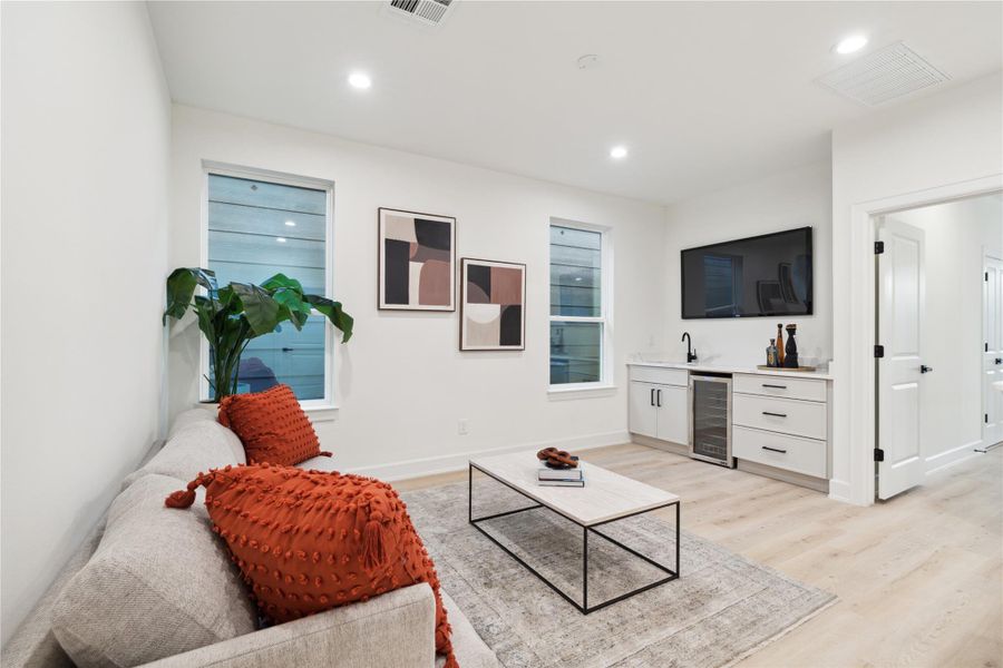 Elevate your entertaining with a stunning second-floor wet bar, featuring a wine cooler, stylish black accent wall, and ample space for your TV. This sophisticated focal point is perfect for hosting guests or unwinding in style.