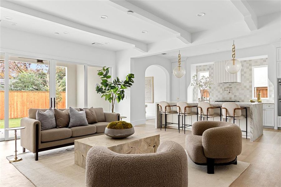 Living area featuring healthy amount of natural light, arched walkways, beam ceiling, recessed lighting, and light wood-type flooring