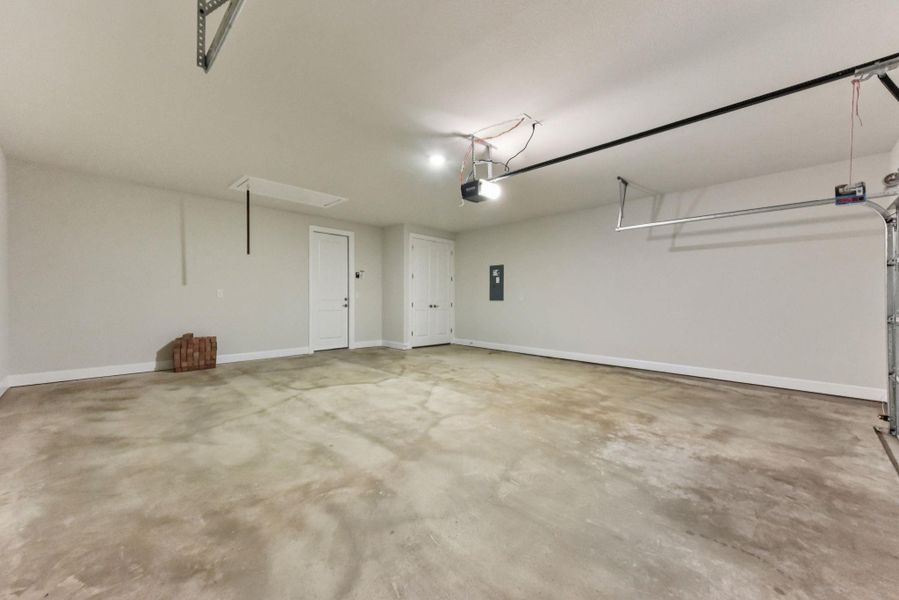 Garage featuring baseboards and electric panel