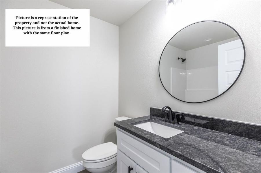 Bathroom vanity featuring a dark countertop, an undermount sink, and a black-framed circular mirror