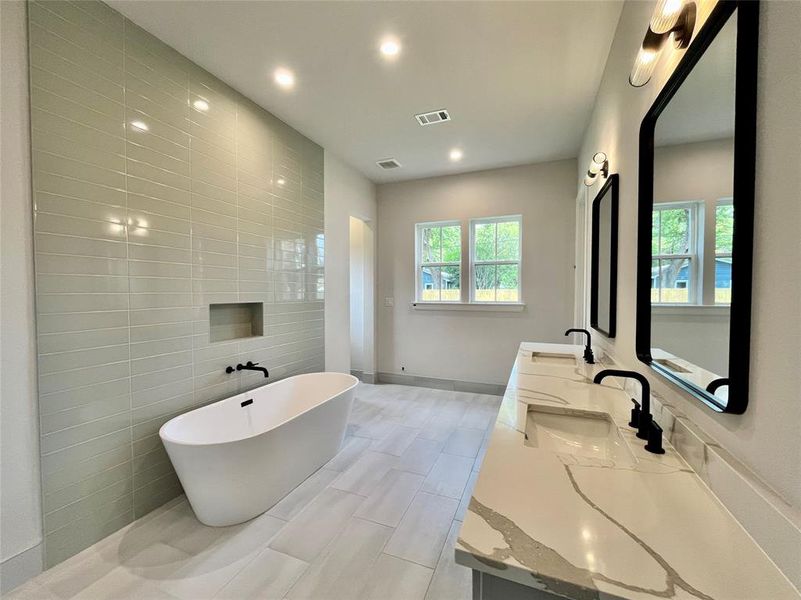 Bathroom featuring a washtub, vanity, and tile walls