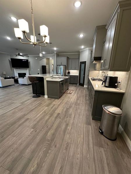 Kitchen featuring ornamental molding, hanging light fixtures, open floor plan, gray cabinetry, and a chandelier