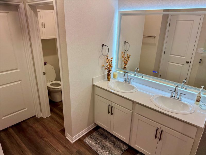 Dual vanity with under-mount sinks,  light-colored counter tops and custom mirror