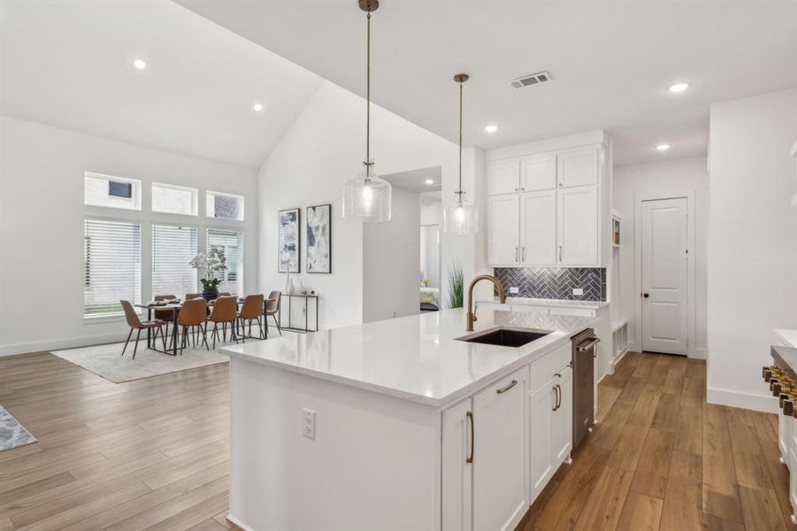 Kitchen featuring light hardwood / wood-style floors, sink, backsplash, and an island with sink