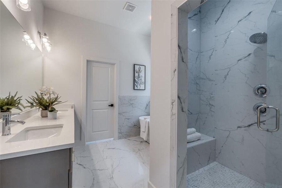 Bathroom with a tile shower, tile flooring, and double vanity