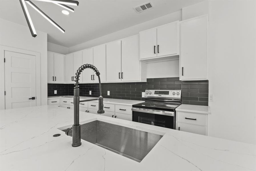 Kitchen with tasteful backsplash, visible vents, electric stove, white cabinetry, and a sink