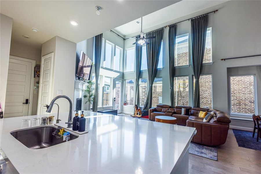 Kitchen featuring healthy amount of natural light, a kitchen island with sink, dark wood-style floors, light stone countertops, and recessed lighting