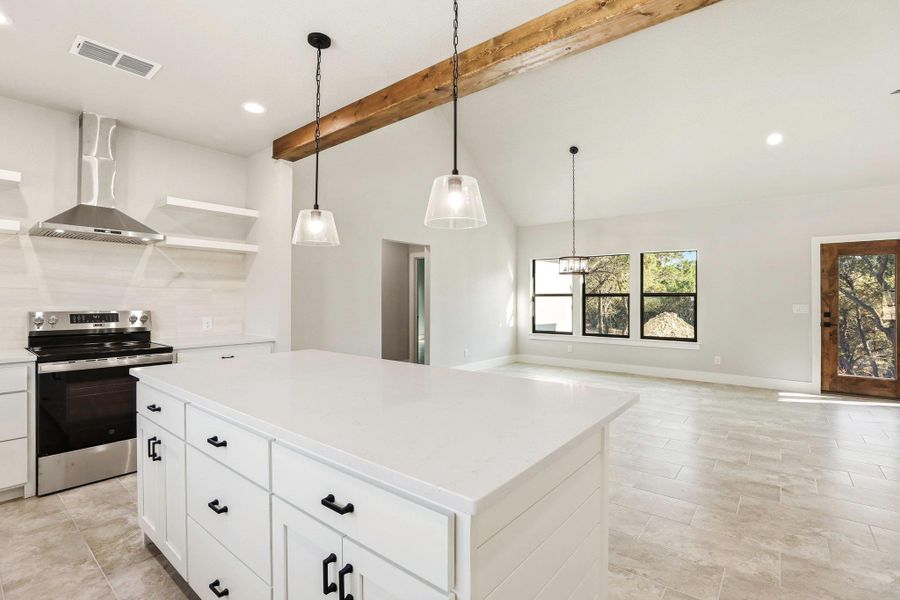 A well-lit kitchen with a spacious island flows into a living area with natural wood accents. A well-lit kitchen with a spacious island flows into a living area with natural wood accents.