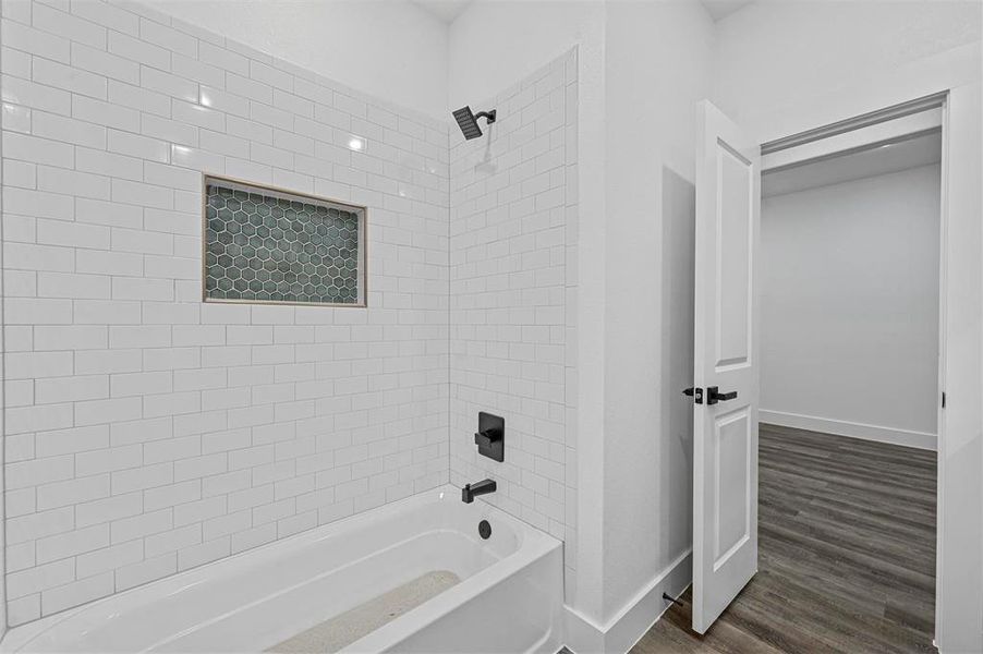 Bathroom with tiled shower / bath combo and hardwood / wood-style flooring