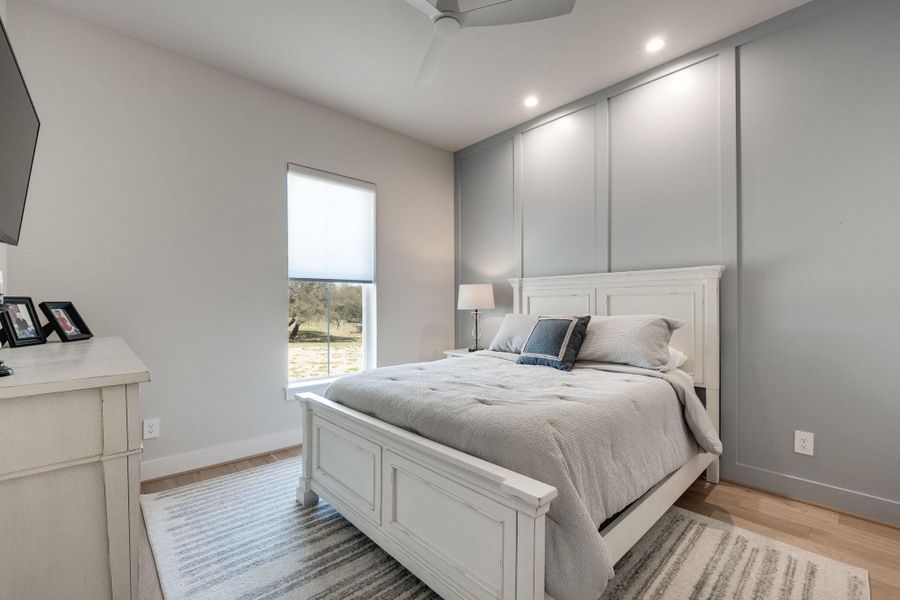 Bedroom featuring ceiling fan, light wood-style floors, recessed lighting, and a decorative wall