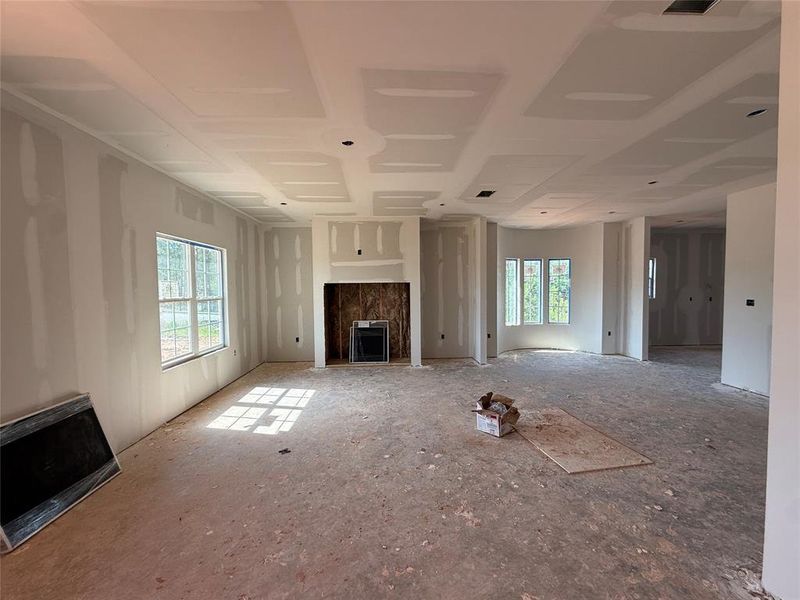 Spacious interior featuring a recessed fireplace, large windows, and a coffered ceiling Spacious interior featuring a recessed fireplace, large windows, and a coffered ceiling