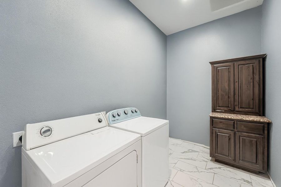 Laundry area with light marble finish flooring and separate washer and dryer Laundry area with light marble finish flooring and separate washer and dryer