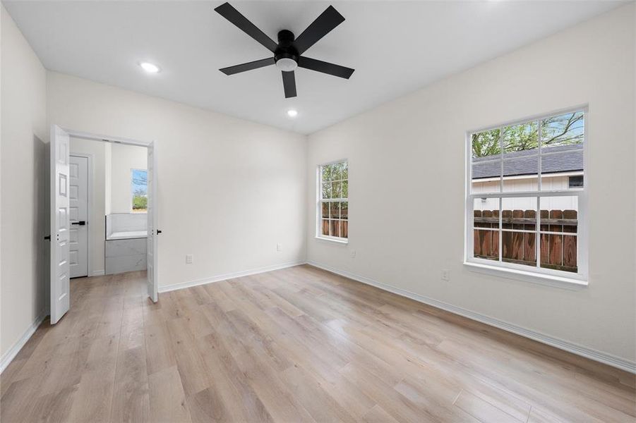 Unfurnished bedroom featuring light wood-style flooring, multiple windows, ceiling fan, and recessed lighting