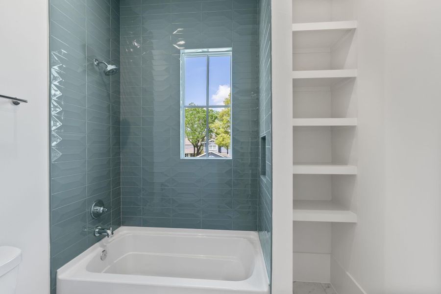 A spacious secondary bathroom features a dual-sink vanity with quartz countertops, modern fixtures, and a large framed mirror, offering both style and functionality.