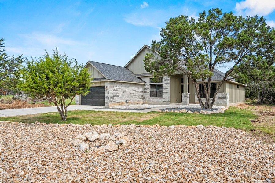 View of front of home with an attached garage, stone siding, and driveway View of front of home with an attached garage, stone siding, and driveway