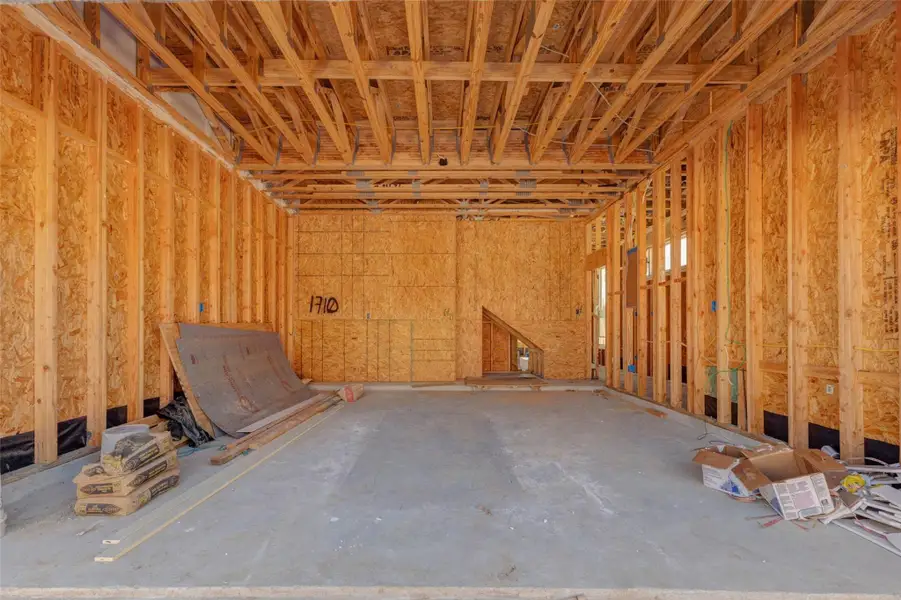 Garage construction view showing a spacious attached garage with exposed framing, concrete flooring, and direct access into the interior of the home. This image highlights the functional entry point, structural progress, and generous garage depth, offering buyers a behind-the-scenes look at the home as it continues toward completion. Garage construction view showing a spacious attached garage with exposed framing, concrete flooring, and direct access into the interior of the home. This image highlights the functional entry point, structural progress, and generous garage depth, offering buyers a behind-the-scenes look at the home as it continues toward completion.