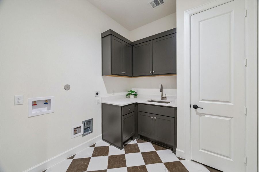 Utility Room with sink and upper and lower cabinets. Quartz countertop and on-trend checkered tile floor.