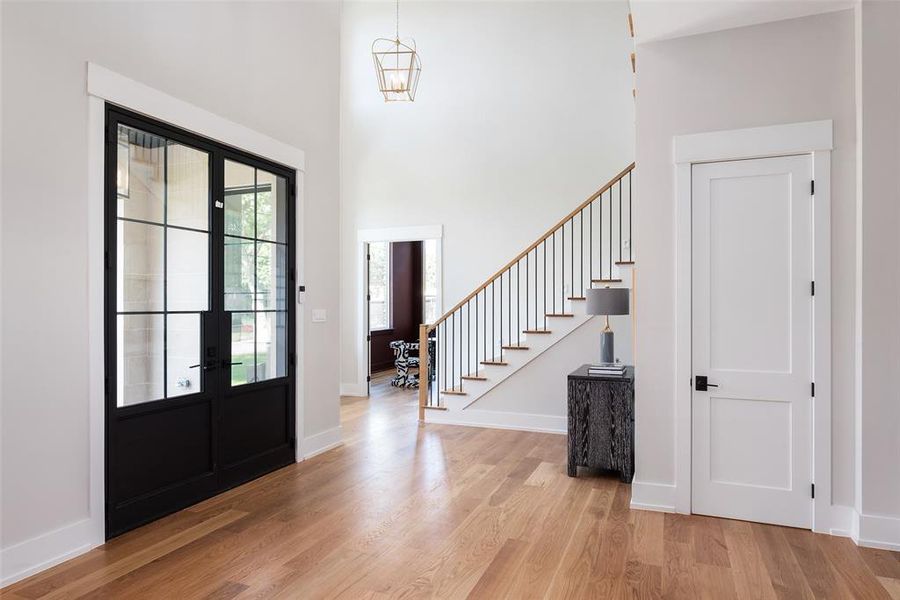 Foyer with a high ceiling, light hardwood / wood-style floors, and french doors