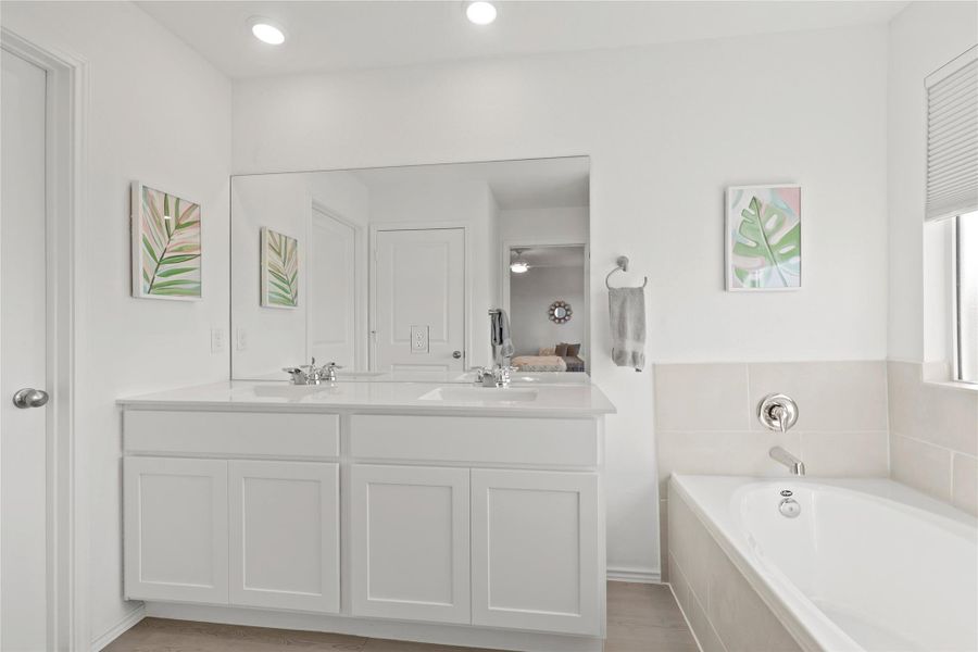 Spa-like primary full bathroom featuring double vanity, a deep garden tub, and crisp white finishes for a clean, contemporary feel.