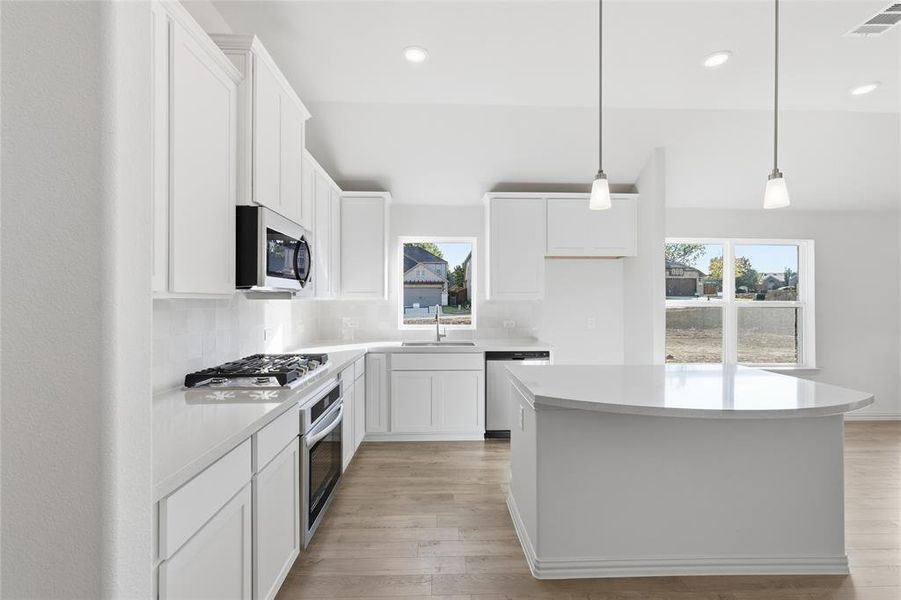Kitchen featuring white cabinets, pendant lighting, light wood-type flooring, stainless steel appliances, and recessed lighting Kitchen featuring white cabinets, pendant lighting, light wood-type flooring, stainless steel appliances, and recessed lighting