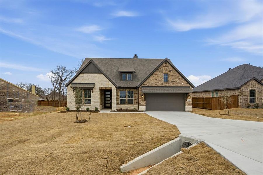 View of front of home featuring concrete driveway, stone siding, roof with shingles, and a chimney View of front of home featuring concrete driveway, stone siding, roof with shingles, and a chimney