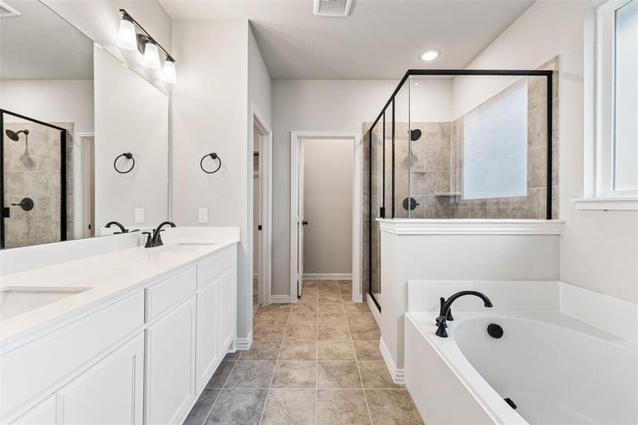 Full bathroom featuring double vanity, a garden tub, a stall shower, and light tile patterned floors Full bathroom featuring double vanity, a garden tub, a stall shower, and light tile patterned floors