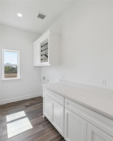 Clothes washing area featuring dark wood-type flooring, cabinets, and hookup for a washing machine