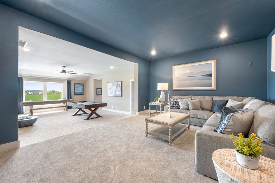 Open-concept living area with blue walls, sectional sofa, and adjoining game room with pool table and shuffleboard