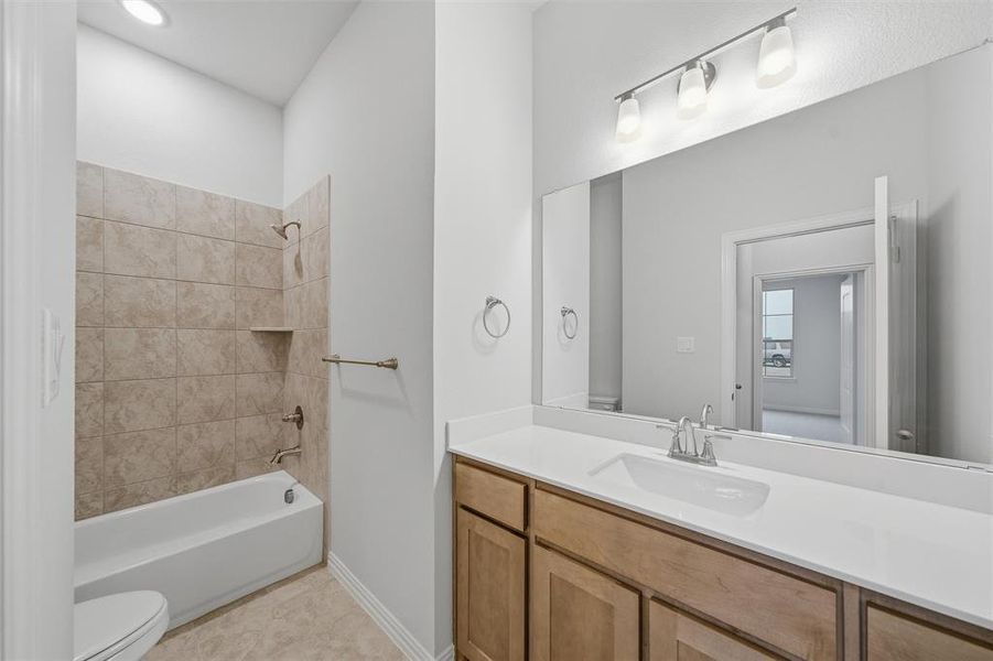 Full bath featuring shower / bath combination, vanity, and light tile patterned floors Full bath featuring shower / bath combination, vanity, and light tile patterned floors