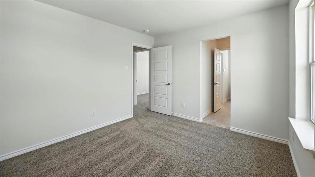 Unfurnished bedroom featuring light carpet and baseboards