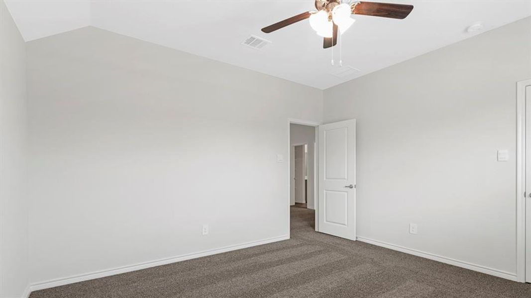 Carpeted room featuring a ceiling fan with integrated lighting, white baseboards, and a paneled interior door