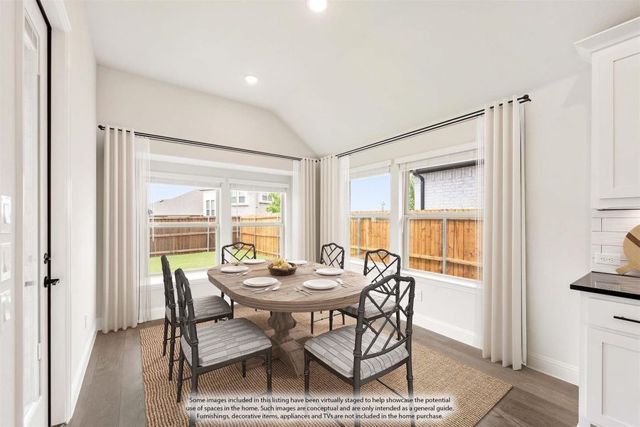 Dining area with round wood table, six chairs, vaulted ceiling, and large windows overlooking backyard Dining area with round wood table, six chairs, vaulted ceiling, and large windows overlooking backyard