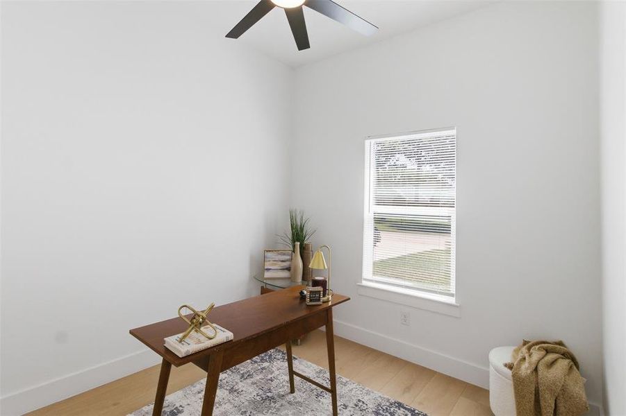 Bright room featuring a single window with blinds, light wood-finish flooring, white walls, and a ceiling fan