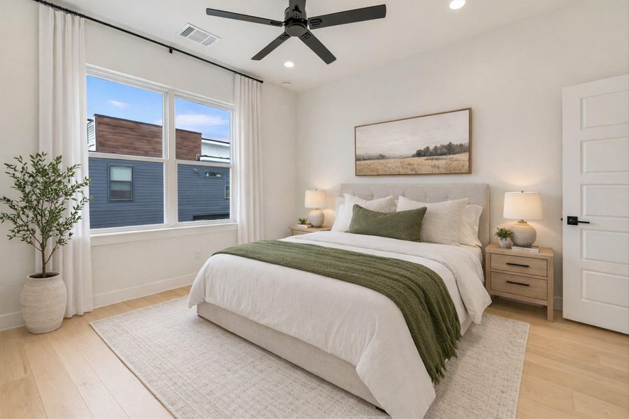 Staged photo. Light-colored hardwood floors and a matte black ceiling fan anchor this versatile second bedroom.