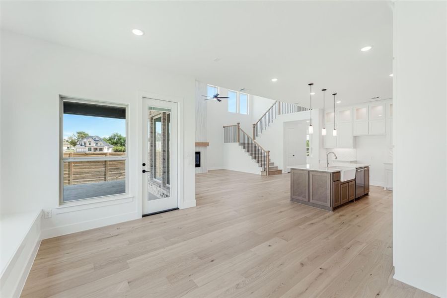 Open-concept living area with hardwood floors, kitchen island, and staircase with high ceilings