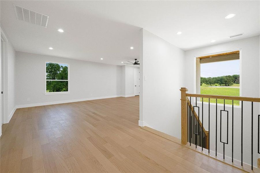 Unfurnished room with healthy amount of natural light, recessed lighting, ceiling fan, light wood-style flooring, and baseboards Unfurnished room with healthy amount of natural light, recessed lighting, ceiling fan, light wood-style flooring, and baseboards