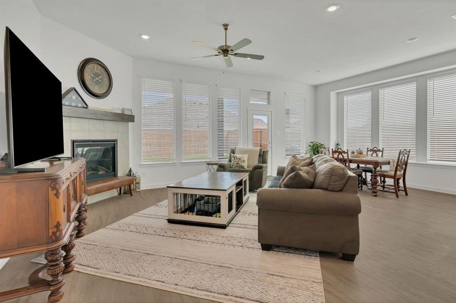 Living area with light wood-style flooring, recessed lighting, a tiled fireplace, and a ceiling fan