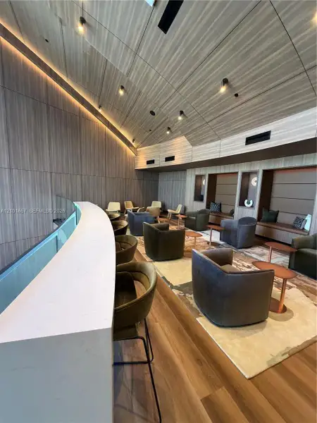 Curved stone-surface breakfast bar with wood-finish flooring, vaulted wood-paneled ceiling, integrated cove lighting, and recessed track lighting