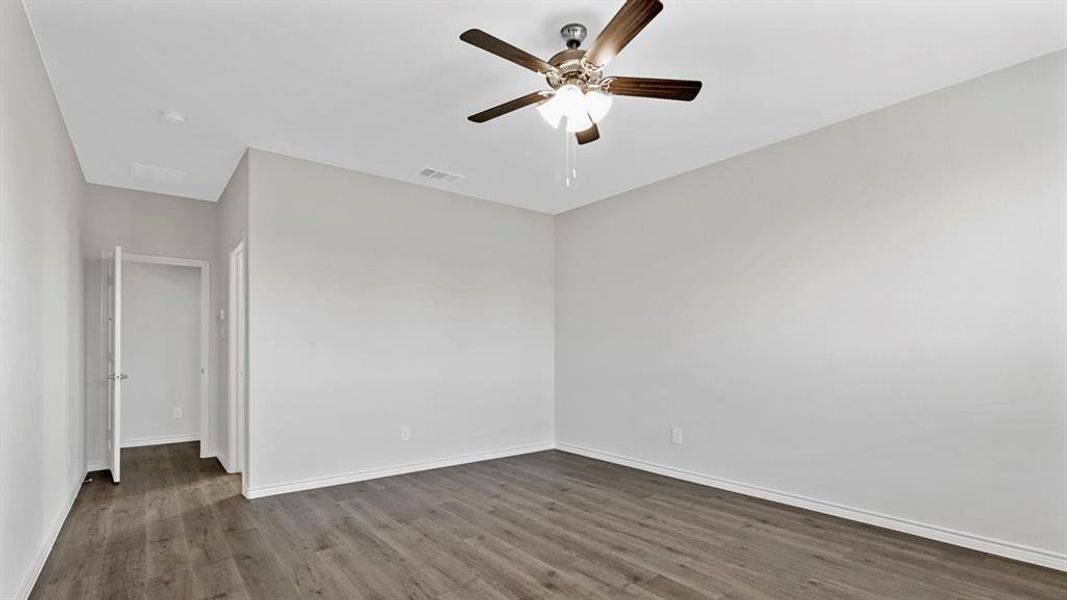 Spacious room featuring wood-finish flooring, light gray walls, and a ceiling fan with integrated lighting
