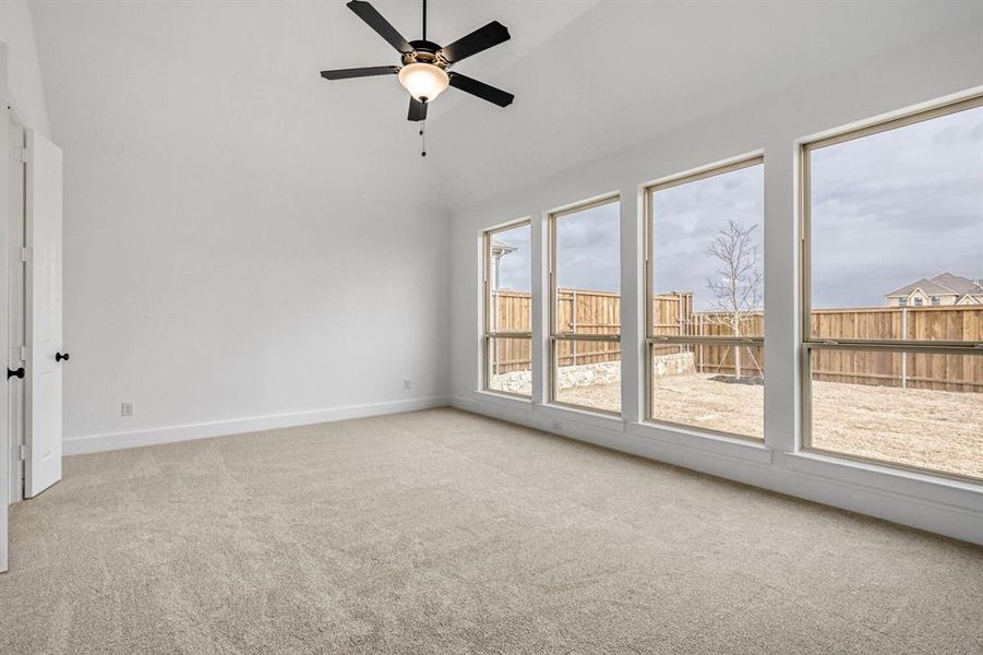 Empty room featuring ceiling fan, light carpet, and vaulted ceiling