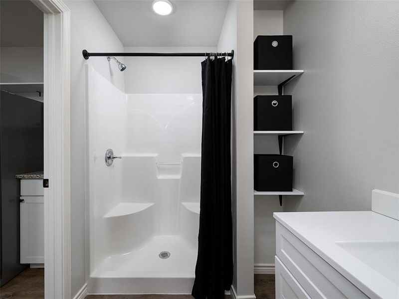 Bathroom featuring a stall shower, vanity, and dark wood-type flooring