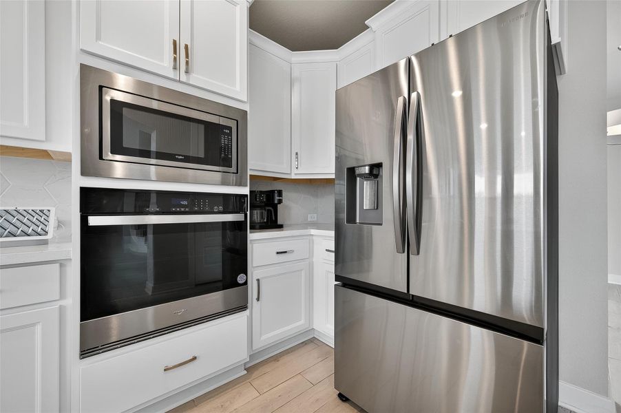 This culinary hub features premium stainless appliances, including a beautiful refrigerator and double oven setup. The clean cabinetry and contemporary finishes create a polished, upscale look.