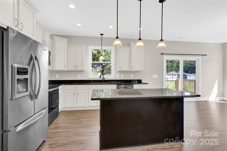 Bright open kitchen w/ island, pendant lights, Stainless appliances.