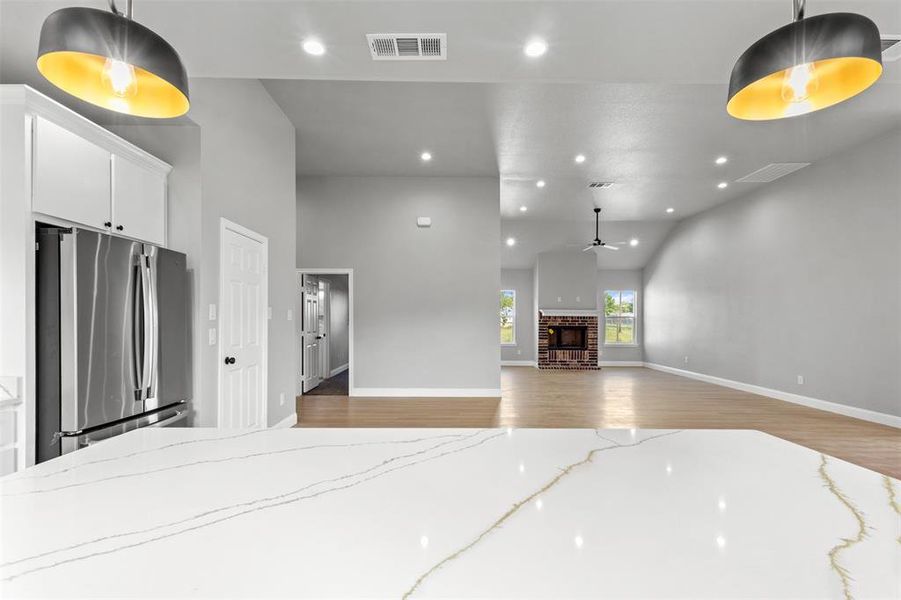 Unfurnished living room featuring recessed lighting, a brick fireplace, light wood-style floors, a ceiling fan, and vaulted ceiling